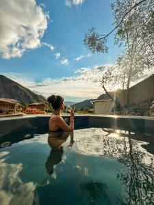 una donna che beve un bicchiere di vino in piscina di Unuwasi Hotel & Villa a Calca