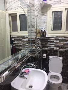 La salle de bains est pourvue d'un lavabo blanc et de toilettes. dans l'établissement شقه فاخره على الكورنيش, à Alexandrie