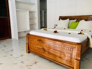 una camera da letto con letto in legno e cuscini bianchi e verdi di Malik Villa Matemwe a Ndizi