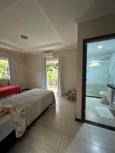 a bedroom with a bed and a bathroom with a shower at CasAmarela in Santa Cruz Cabrália
