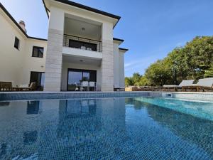 a large swimming pool in front of a house at Apartmani Mariosa in Vrbnik