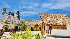 a couple of houses with palm trees in the background at Malik Villa Matemwe in Ndizi