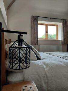 um quarto com uma cama com um candeeiro em The Old Dairy. A beautifully converted barn with stunning views em Charlecote