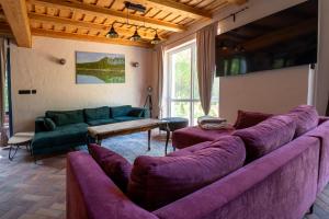 salon z fioletowymi kanapami i stołem w obiekcie Dom Biały, willa nad jeziorem w Gawrych Rudzie