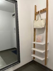 Un espejo al lado de un estante con un bolso. en XOX Comfort Obregia, en Bucarest