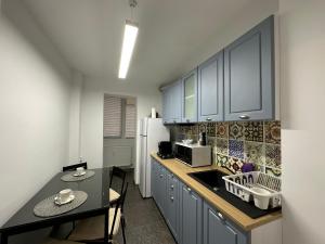 Una cocina con gabinetes azules y una mesa y una encimera. en XOX Comfort Obregia, en Bucarest