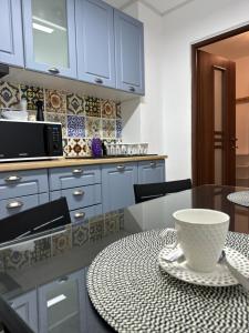 una cocina con armarios azules y una mesa con un tazón. en XOX Comfort Obregia, en Bucarest
