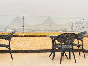 Jewel Grand Museum & Pyramids View في Giza: كرسيين وطاولة مطلة على الاهرامات