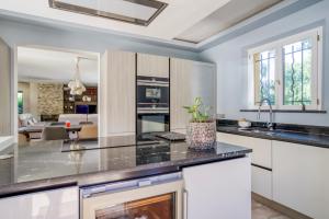 a kitchen with white cabinets and a living room at Villa Golf les Cigales in Mouans-Sartoux