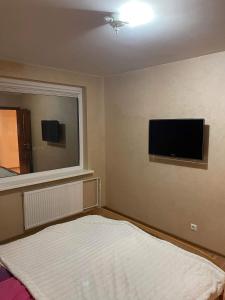 een slaapkamer met een bed en een flatscreen-tv bij Dainai Apartments in Šiauliai