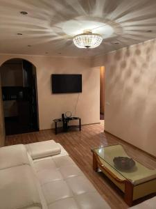 een woonkamer met een witte bank en een tv bij Dainai Apartments in Šiauliai