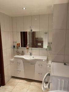 een witte badkamer met een wastafel en een spiegel bij Dainai Apartments in Šiauliai