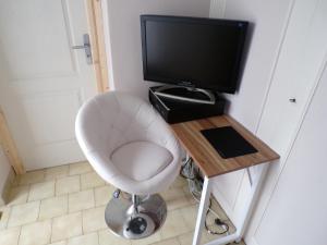 una camera con sedia bianca e televisore di Suite Royale dans Vôtre maisonnette indépendante avec terrasse Privée ! a Montmorillon