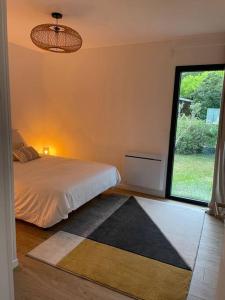 1 dormitorio con cama y ventana grande en Agréable maison individuelle proche Bordeaux, en Ambarès-et-Lagrave
