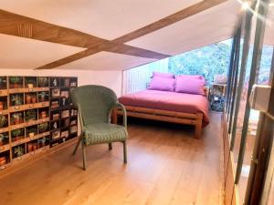 a bedroom with a bed and a chair and a window at "L'Atelier de Pierre" Gîte Atypique in Saint-Cyr