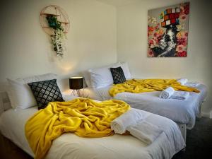 two beds with a yellow blanket on top of them at 4 Bedroom House -Sleeps 10- Big Savings On Long Stays! in Canterbury
