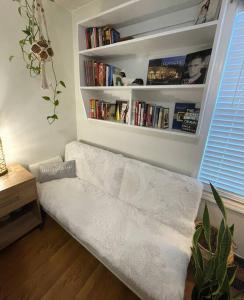 eine weiße Couch in einem Wohnzimmer mit Bücherregal in der Unterkunft *Candlewicke Vista Nashville Retreat* Pets Welcome! in Spring Hill
