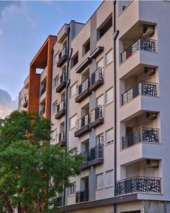 ein Apartmenthaus mit Balkon und einem Baum in der Unterkunft Apartman ENEM in Mostar