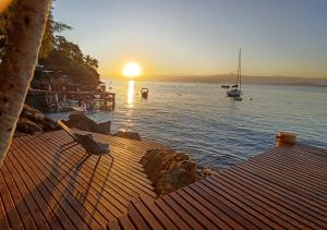 una puesta de sol sobre un cuerpo de agua con un barco en Saracura, en Praia de Araçatiba