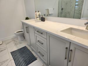 a white bathroom with a sink and a mirror at Good Fortune Residence, Ottawa in Ottawa