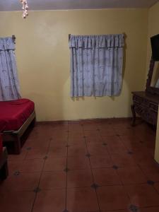 ein Wohnzimmer mit Vorhängen und Fliesenboden in der Unterkunft Cabañas vero in Caleta de Campos