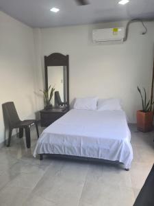 een slaapkamer met een wit bed, een stoel en een spiegel bij CasaSpa in La Dorada