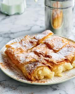 einen Teller French Toast mit Puderzucker drauf in der Unterkunft Eleni Rooms in Parikia