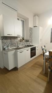 a kitchen with white cabinets and a sink and a table at Perla de Mar a 20m dalla spiaggia in Letojanni