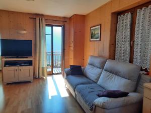 a living room with a couch and a television at Appartamento la Regina del Lago in Molveno