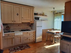 eine Küche mit Holzschränken und einem weißen Kühlschrank in der Unterkunft Appartamento la Regina del Lago in Molveno