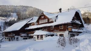 duży drewniany budynek pokryty śniegiem w obiekcie Schütterhof w mieście Ramsau am Dachstein