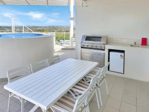 uma mesa branca e cadeiras numa cozinha com banheira em Kirra Penthouse with Private Spa em Gold Coast