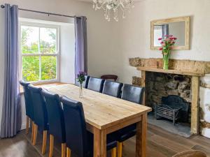 a dining room with a wooden table and chairs and a fireplace at The Farmhouse in Pelcomb