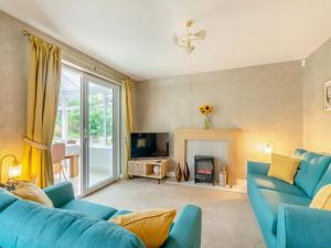 a living room with blue couches and a fireplace at Cherry Tree Corner in Ashbourne