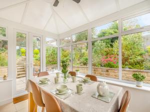 a dining room with a table and chairs and windows at Cherry Tree Corner in Ashbourne