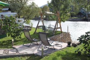 a group of chairs sitting on a patio near a lake at AM Una Lux House in Bihać