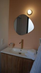 La salle de bains est pourvue d'un lavabo et d'un miroir. dans l'établissement Jolie Maison avec piscine intérieure à 5 minutes des plages, à Landunvez