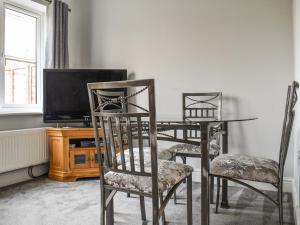 a dining room with a table and chairs and a tv at Meadow Walk in Sudbury