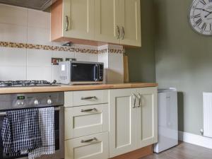 a kitchen with white cabinets and a clock on the wall at Meadow Walk in Sudbury
