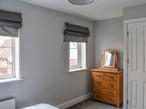 a bedroom with a bed and a dresser and two windows at Meadow Walk in Sudbury