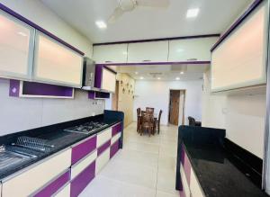 a kitchen with purple and white cabinets and a table at kolte patil 24k allura in Pune