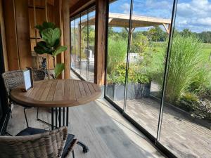 een veranda met een houten tafel en glazen deuren bij 't Heidepaleis in Garderen