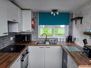 a kitchen with white cabinets and a window at 18 Sea Valley Bideford Bay Park Dean in Bideford