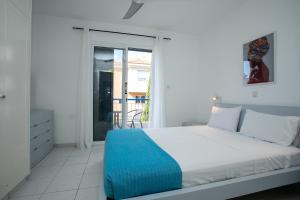 Casa Del Sol Townhouse in Iris Village Paphos في بافوس: غرفة نوم بيضاء مع سرير وشرفة