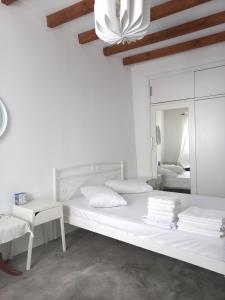 a white bedroom with a large bed and a mirror at Stella' s house Castle of Chora Naxos in Naxos Chora
