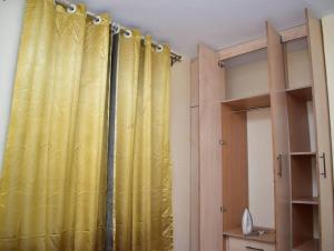 a yellow curtain in a room with some shelves at Marie's 1br near Sarovawoodlands in Nakuru