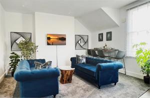 a living room with two blue couches and a table at Perfectly located City Centre apartments in Exeter