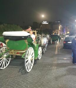 a green horse drawn carriage on a street at night at Ryad Laârouss in Marrakesh