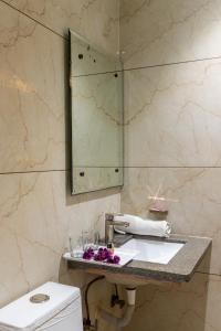 W łazience znajduje się umywalka, lustro i toaleta. w obiekcie Hotel Morya Meghdoot, Bhopal w mieście Bhopal