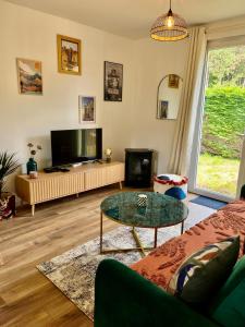 a living room with a couch and a tv at Maison Evasion Voyage parking et jardin by Art de Voyager in Étretat